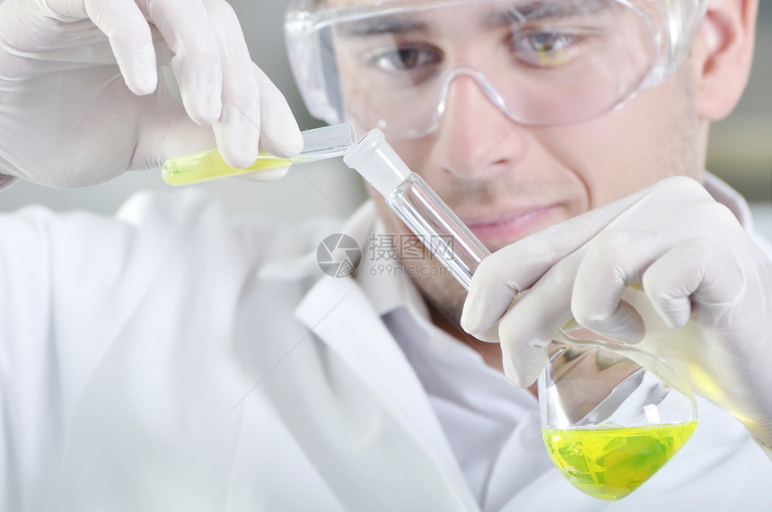 有吸引力的年轻博士生科学家在化学实验室观察溶液蒸馏后的黄色指图片