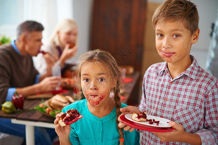 在父母背景上吃甜派的有趣孩子的肖像他图片
