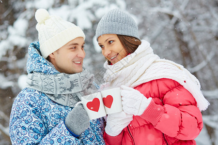 欢快的情侣拿着红心杯和在冬季图片
