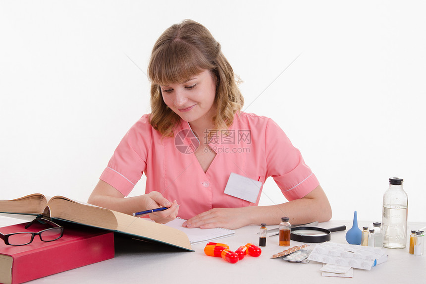 坐在桌边的药剂师阅读一本厚图片