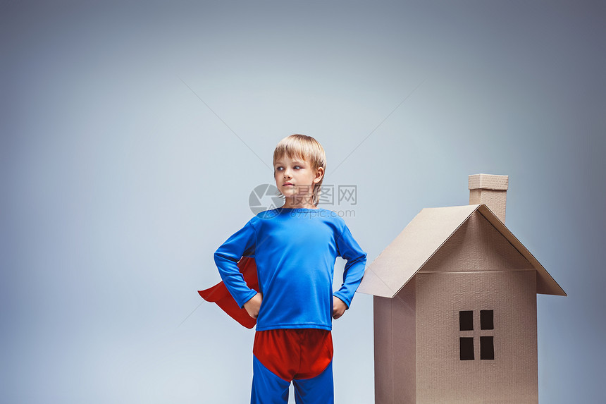 穿着纸板房子的超人服装的男孩图片