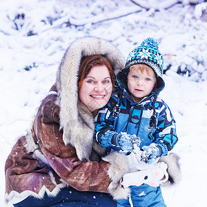 年轻母亲和小孩男在美丽的冬日与户外图片