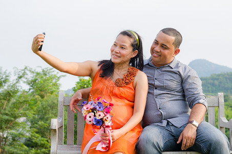 亚洲怀孕妻子和丈夫手机照片图片
