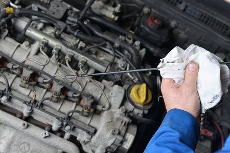 一名汽车机械师在例行维修期间检查汽车发动机的石油水平单图片