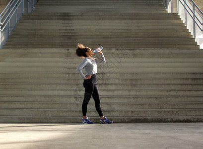 一名运动妇女用瓶装饮用水喝图片