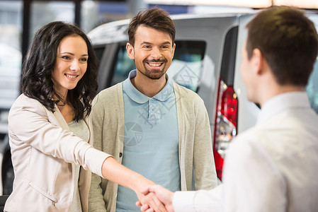 年轻夫妇感激的销售经理在汽车沙龙的建议图片