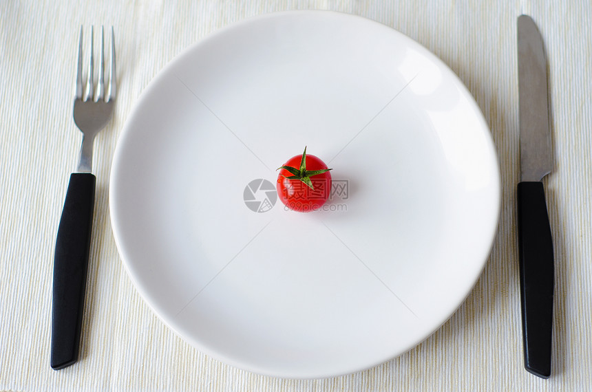 西红柿用叉子和刀放在盘子里图片