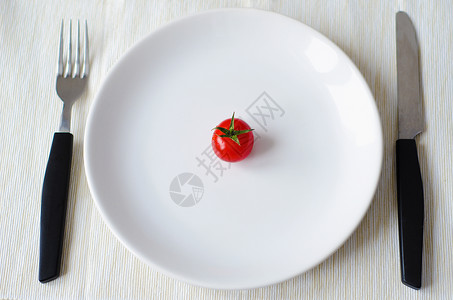 西红柿用叉子和刀放在盘子里图片