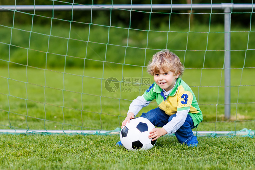 有趣的快乐小男孩踢足球和足球图片
