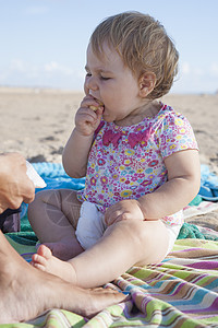 一年婴儿在海滩妈旁边吃香蕉的毛巾上图片