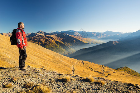 山顶的男登山者在日落时放松图片