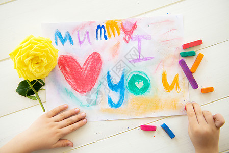 小女孩正在为母亲节用粉笔画明信片她写了妈我爱你黄图片
