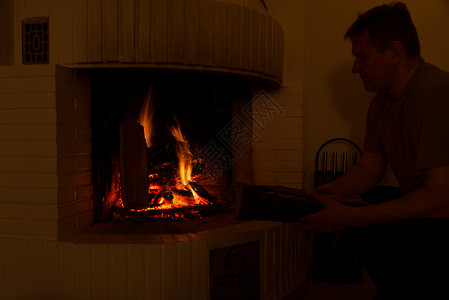 男人在燃烧的壁炉里加柴火图片