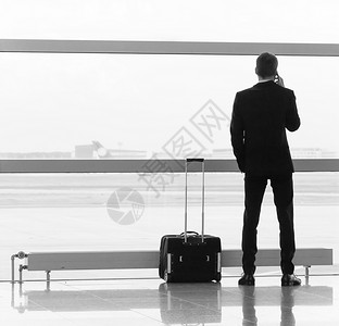 在机场提着行李的男人黑与白图片
