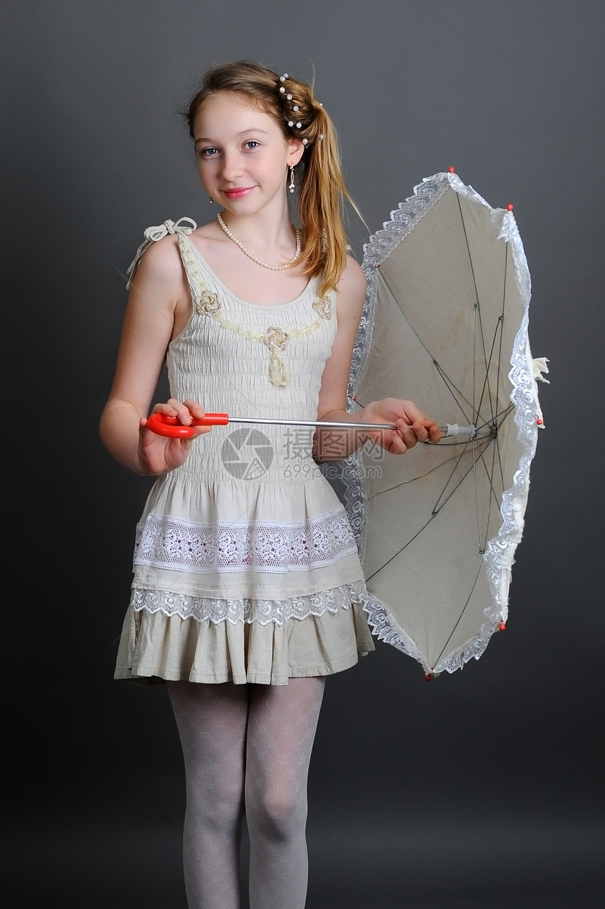 1213岁微笑的小女孩站在工作室里带着遮阳伞图片