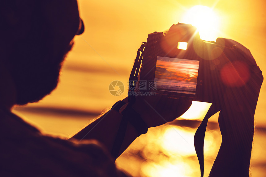 在日落时使用其专业数码SLR摄影机的男子旅行数码摄影概念照片图片