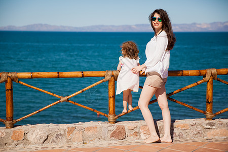 一个西班牙裔年轻女肖像和她女儿在沙滩上渡过一些假期图片