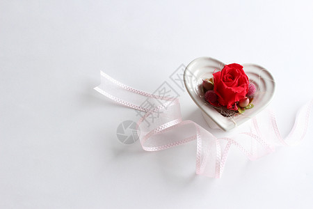 红玫瑰保存的花朵在心形白色容器中Valenti背景图片