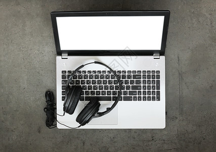 在纹理桌面背景上使用耳机和空白屏幕计算机笔记本电脑创作音乐概念的工图片