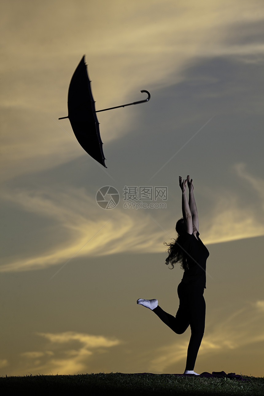 日落时带着雨伞在户外跳跃的年轻女子图片