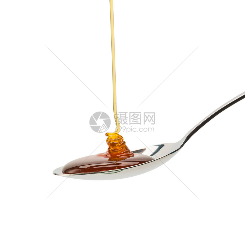 一个银勺子与生物蜂蜜隔绝在白色背景上在演播室里拍图片