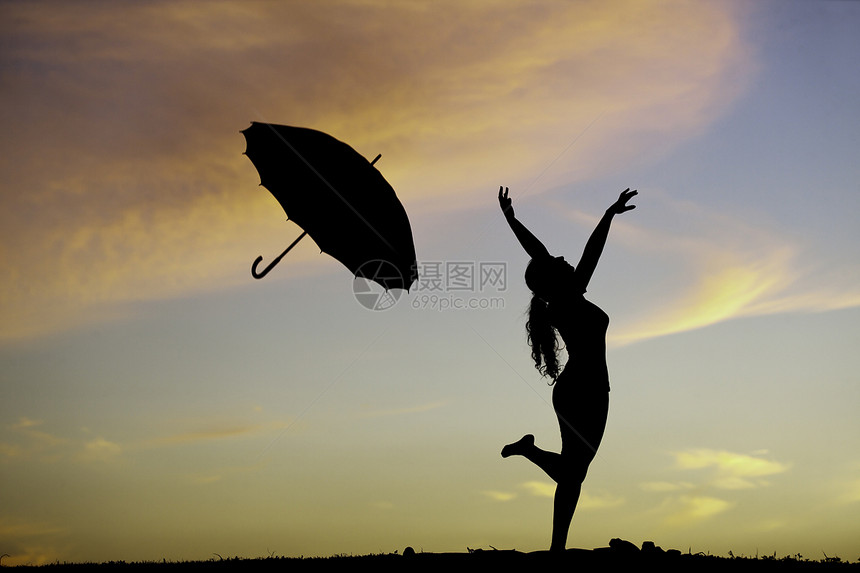 日落时带着雨伞在户外跳跃的年轻女子图片