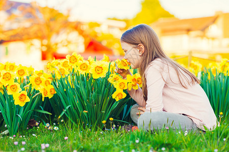 可爱的小女孩在日落的时候在公园里玩花儿闻着图片