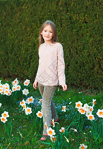 7岁的可爱小女孩在春天公园玩花草间游荡图片