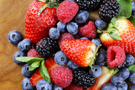 浆果分类木质背景中的覆盆子黑莓草莓蓝莓图片