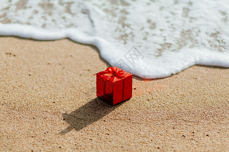 在热带海滩上的红色盒子里的礼物呈现在海中流动的红色盒子海滩图片