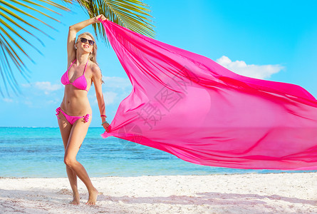 穿着粉红色比基尼女人在热带海滩风中图片