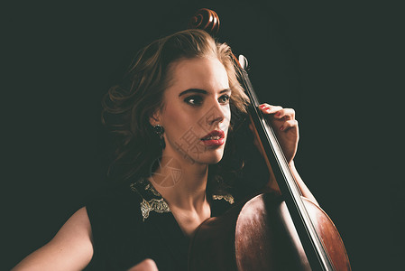 在音乐学院的演奏会里年轻有抱负的女音乐家玩大提琴低角度近图片