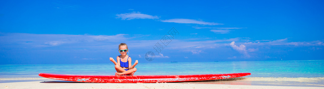 小女孩在绿松石海的冲浪板上游泳图片