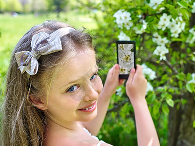 女孩在电话上拍着开花的樱桃图片