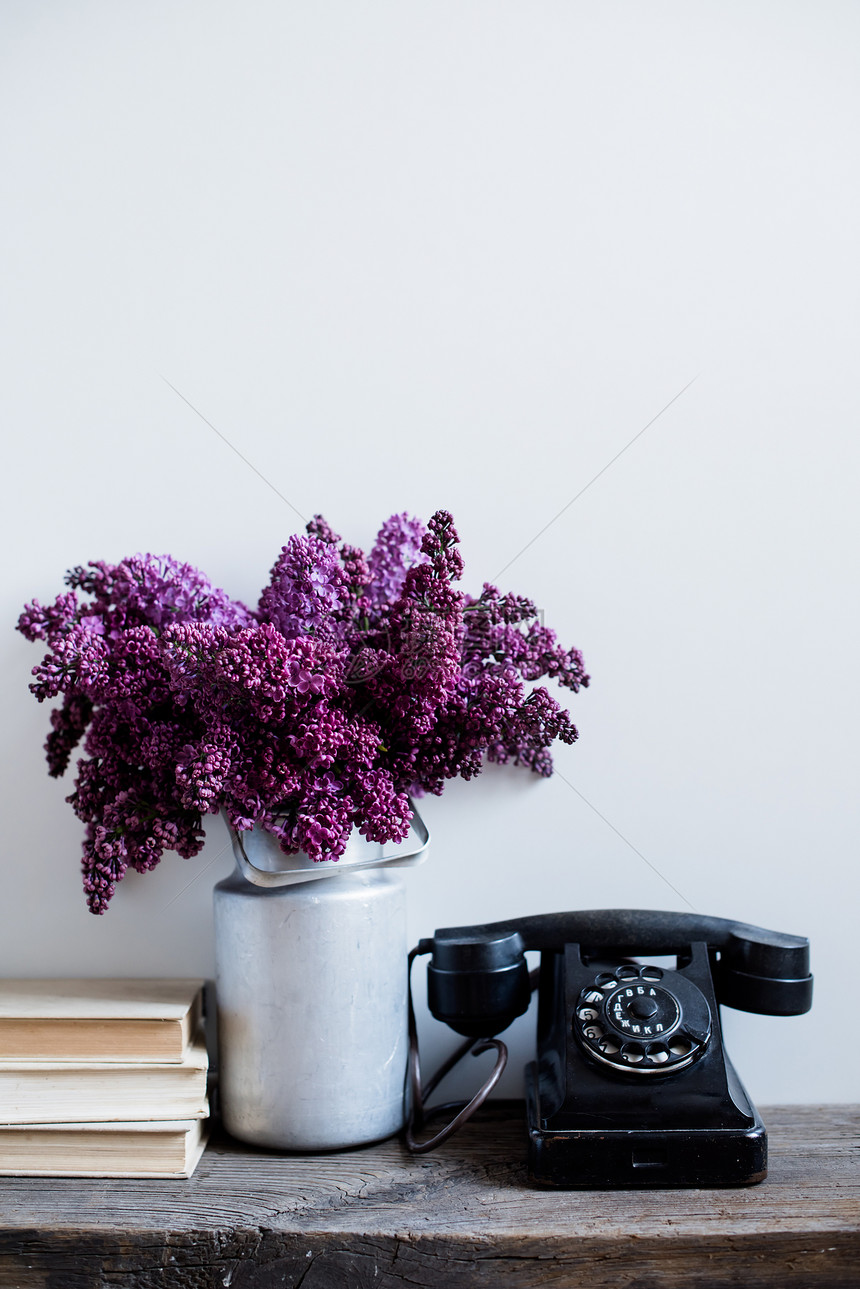 家居室内装饰花瓶中的丁香花老式旋转电话和质朴木桌上的书籍图片