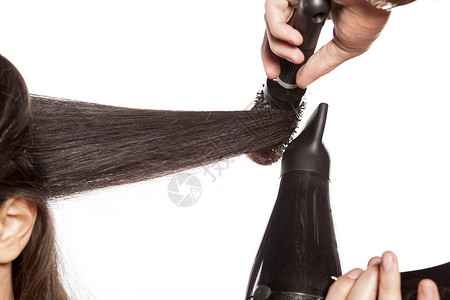 理发师用吹风机和梳子为客户做头发图片