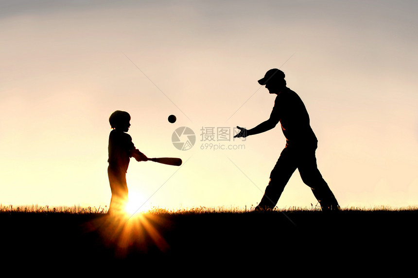 一个父亲和他年幼的孩子在外面打棒球的剪影图片
