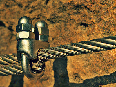 镀铬螺丝扣钩和索环的细节用螺丝卡钩固定在一起的铁绞绳锚定在岩石图片