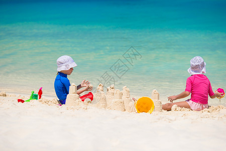 热带度假期间玩沙滩玩具的小可爱女孩的图片