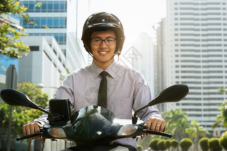 年轻的亚洲商人通勤上班该男子骑着一辆带白色头盔的摩托车图片