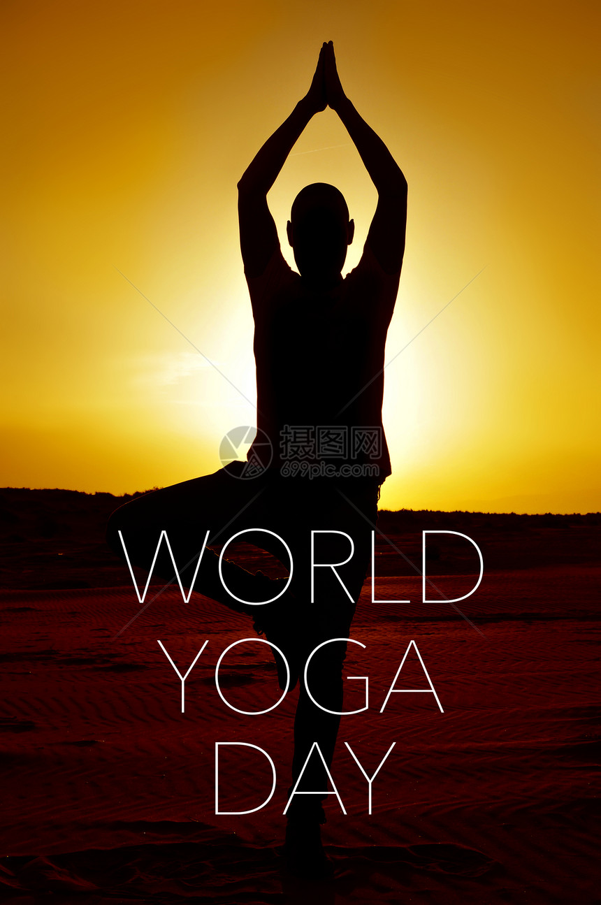一个年轻瑜伽男子练习这棵树在日落和文字世界瑜伽日的背光图片