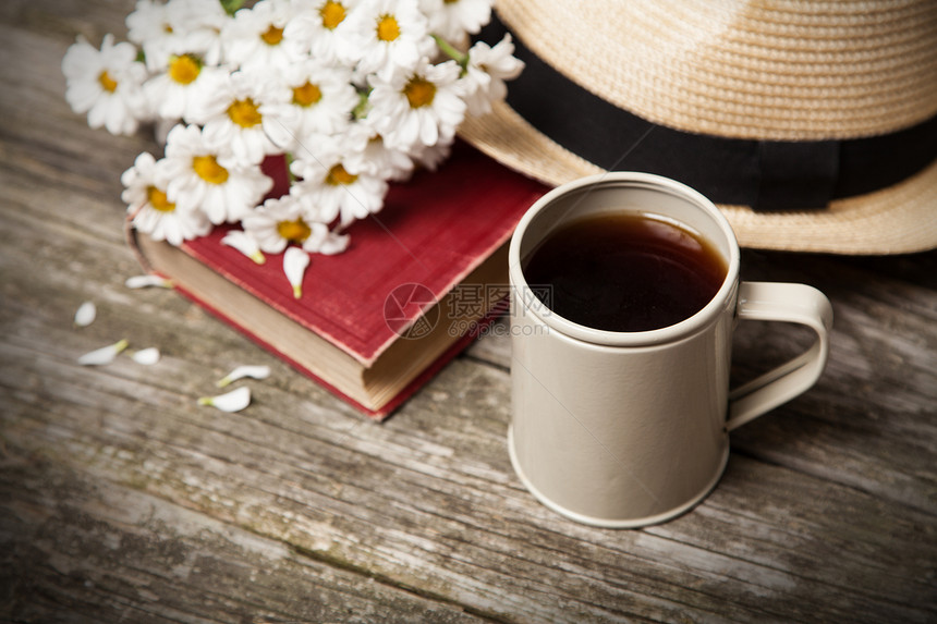咖啡雏菊和木制背景上的一本书图片