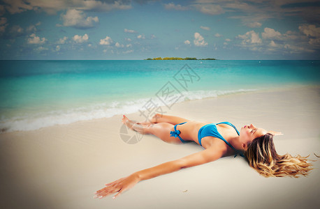 棕褐色的女孩躺在沙滩上的海边图片