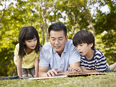 生活在草地上的亚洲父亲和孩子在公园里图片