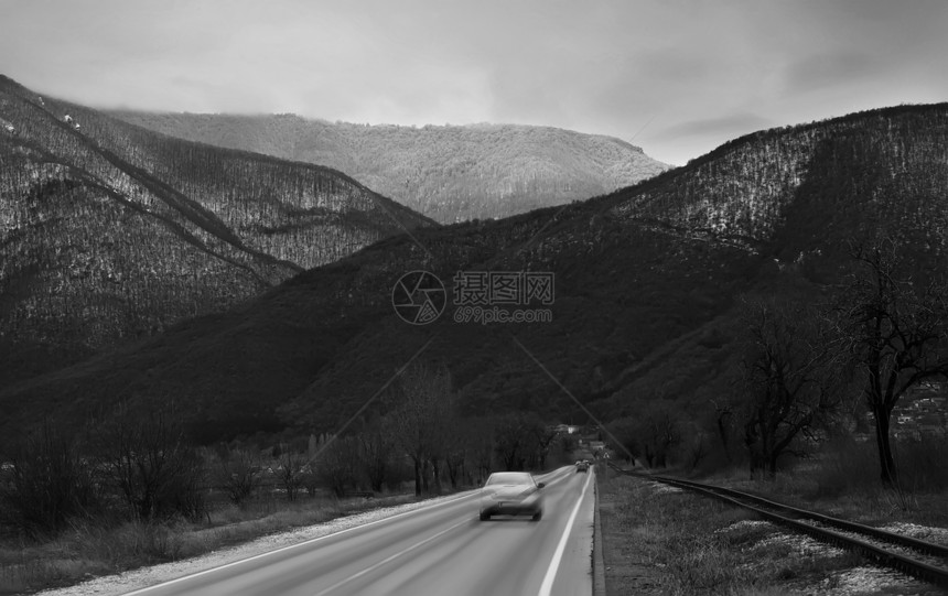 高山附近的汽车驱动器模糊不清的黑白冬季道图片