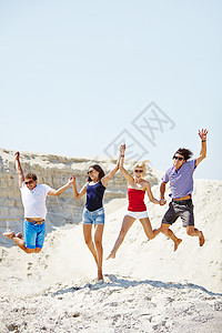 兴奋的年轻人在跳上沙滩图片