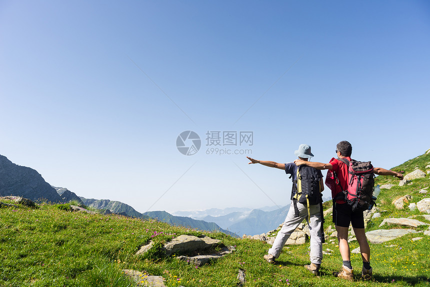 双臂伸展的登山徒步者在山顶达到目标图片