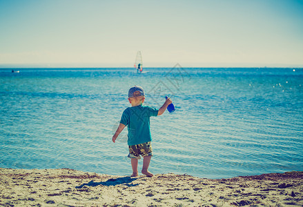 小孩在夏日天气好时在海边玩耍照片带有古背景图片