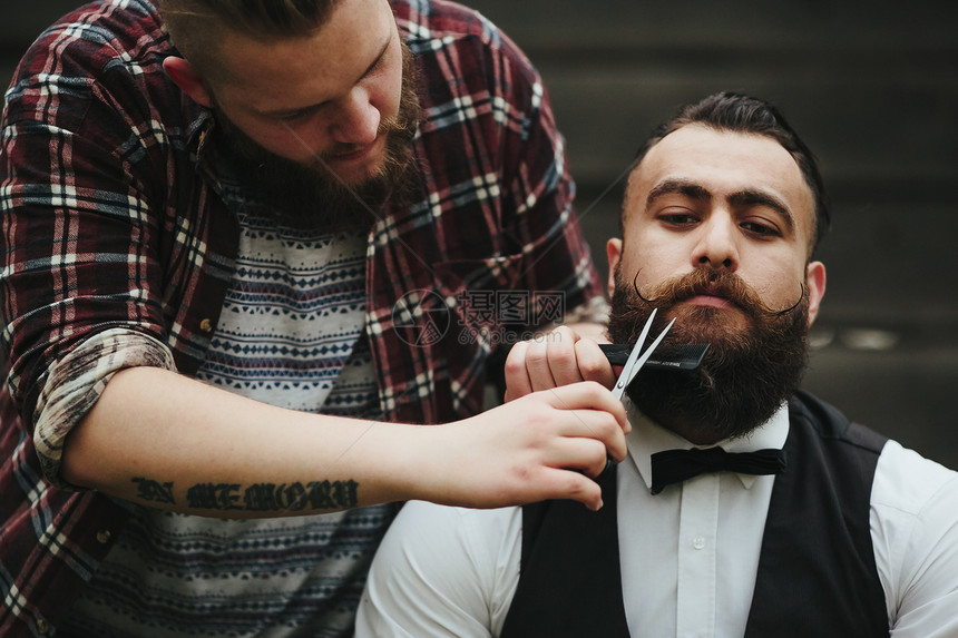 理发师在复古的氛围中给留胡子的人刮胡子图片