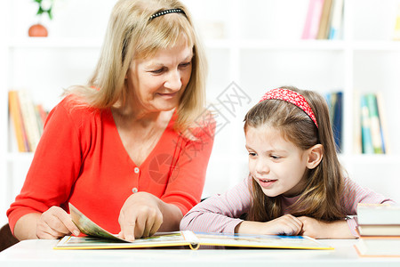 外祖母帮助小女孩学习读书并让图片